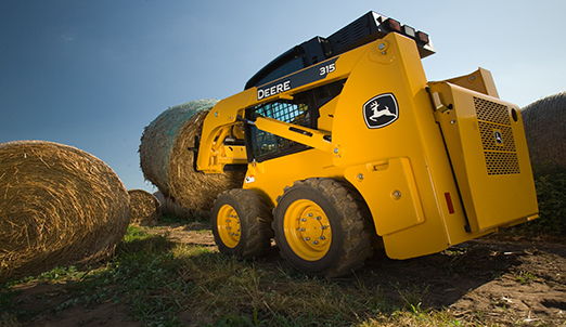 Skid steer with a round hay bale on Deere's bale spear attachment