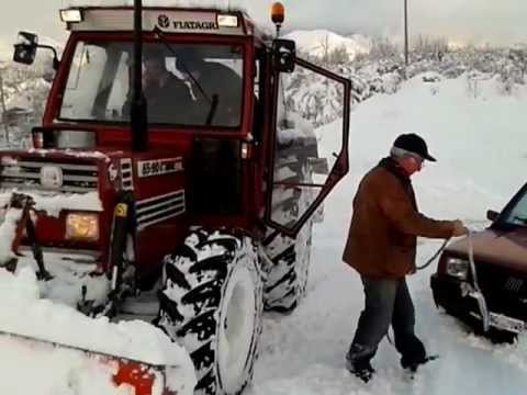 Lo spalatore libera il bobcat col trattore contro bobcat nella neve